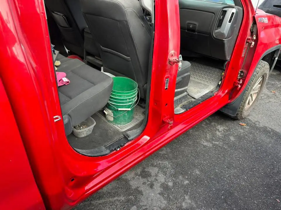 bodywork complete on a red truck up on a lift at Reflections Auto in Auburn Maine