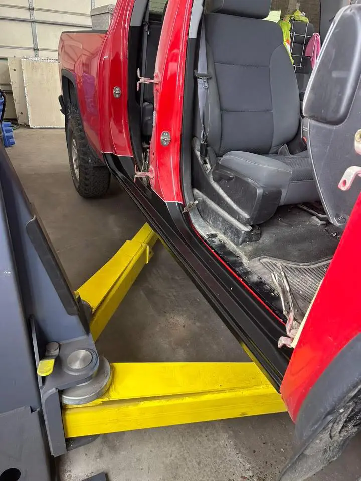bodywork underway on a red truck up on a lift at Reflections Auto in Auburn Maine